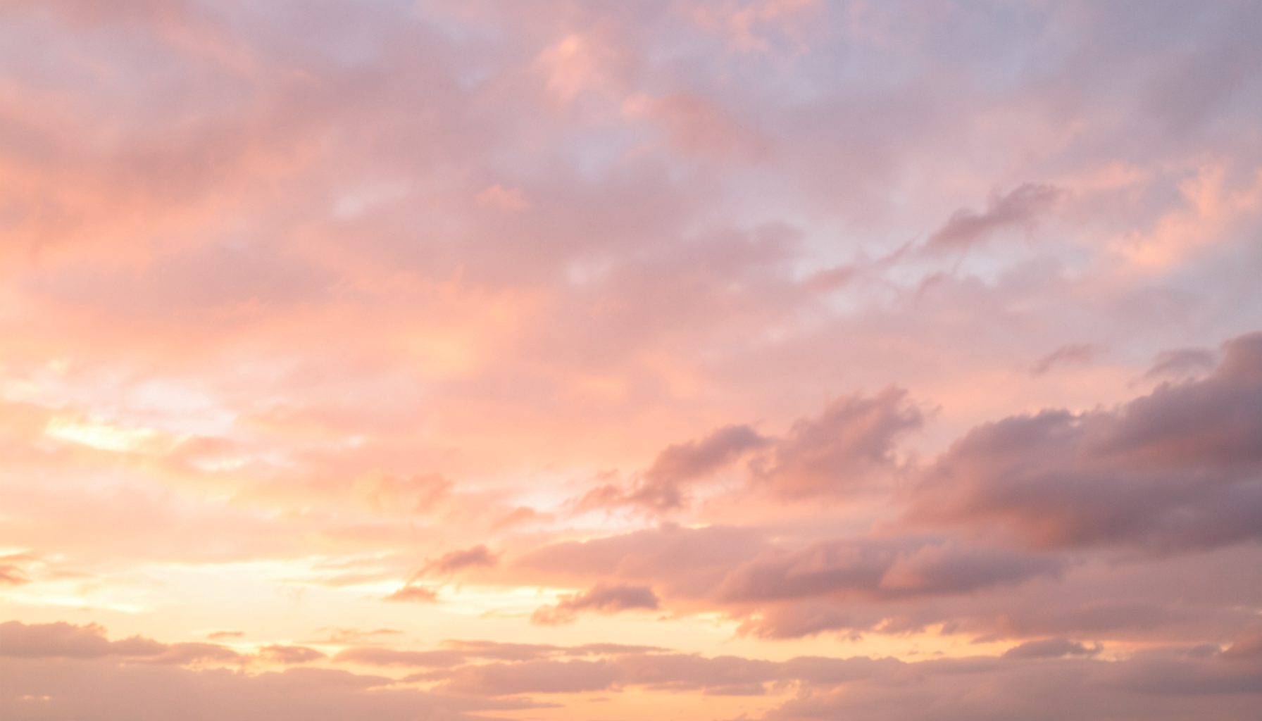 Un cielo al atardecer con nubes suaves en tonos rosados y dorados, transmitiendo calma y esperanza.